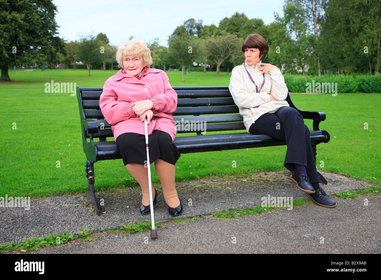 Old lady with carer showing contempt on park bench Stock Photo - Alamy
