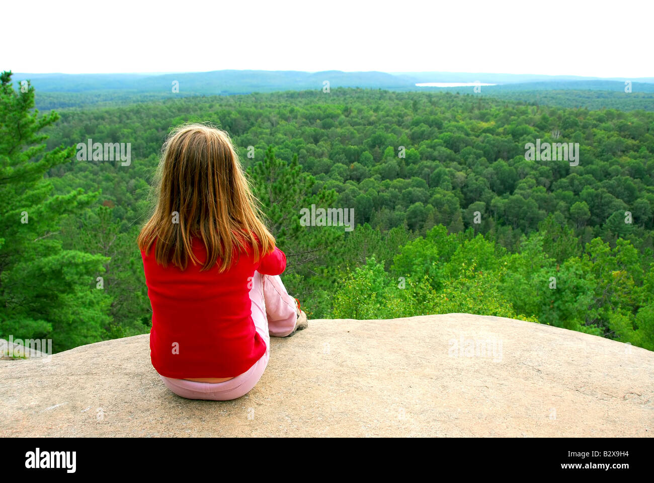 Young girl sitting on an edge of a cliff Stock Photo - Alamy