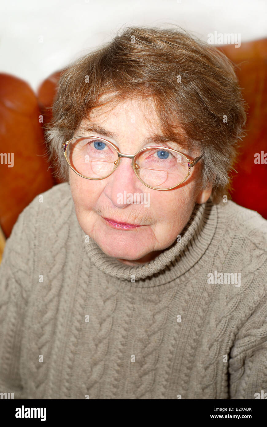 Portrait of a senior woman sitting on a couch Stock Photo - Alamy