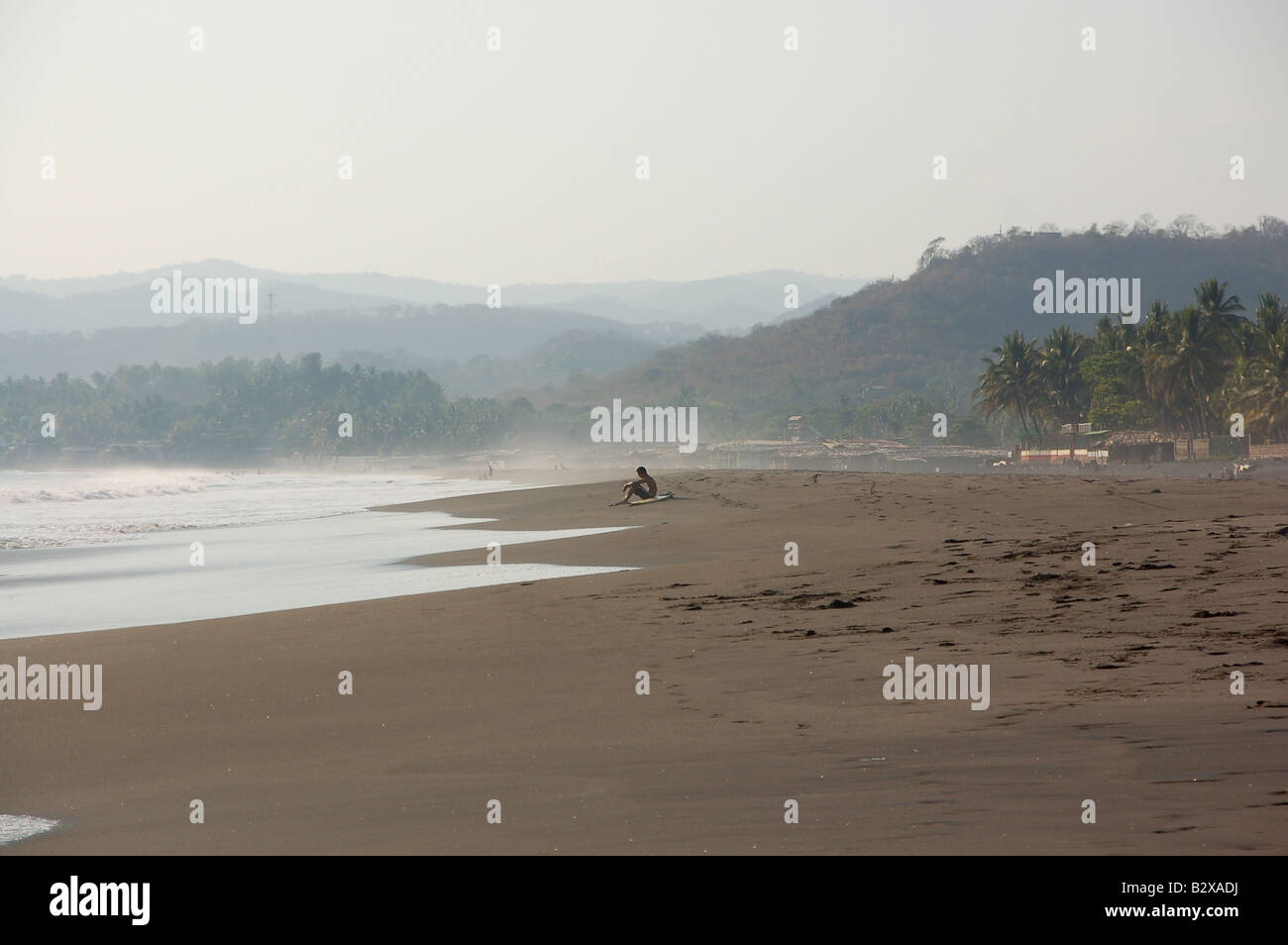 A surfer takes a break on the beach at El Zonte, El Salvador Stock