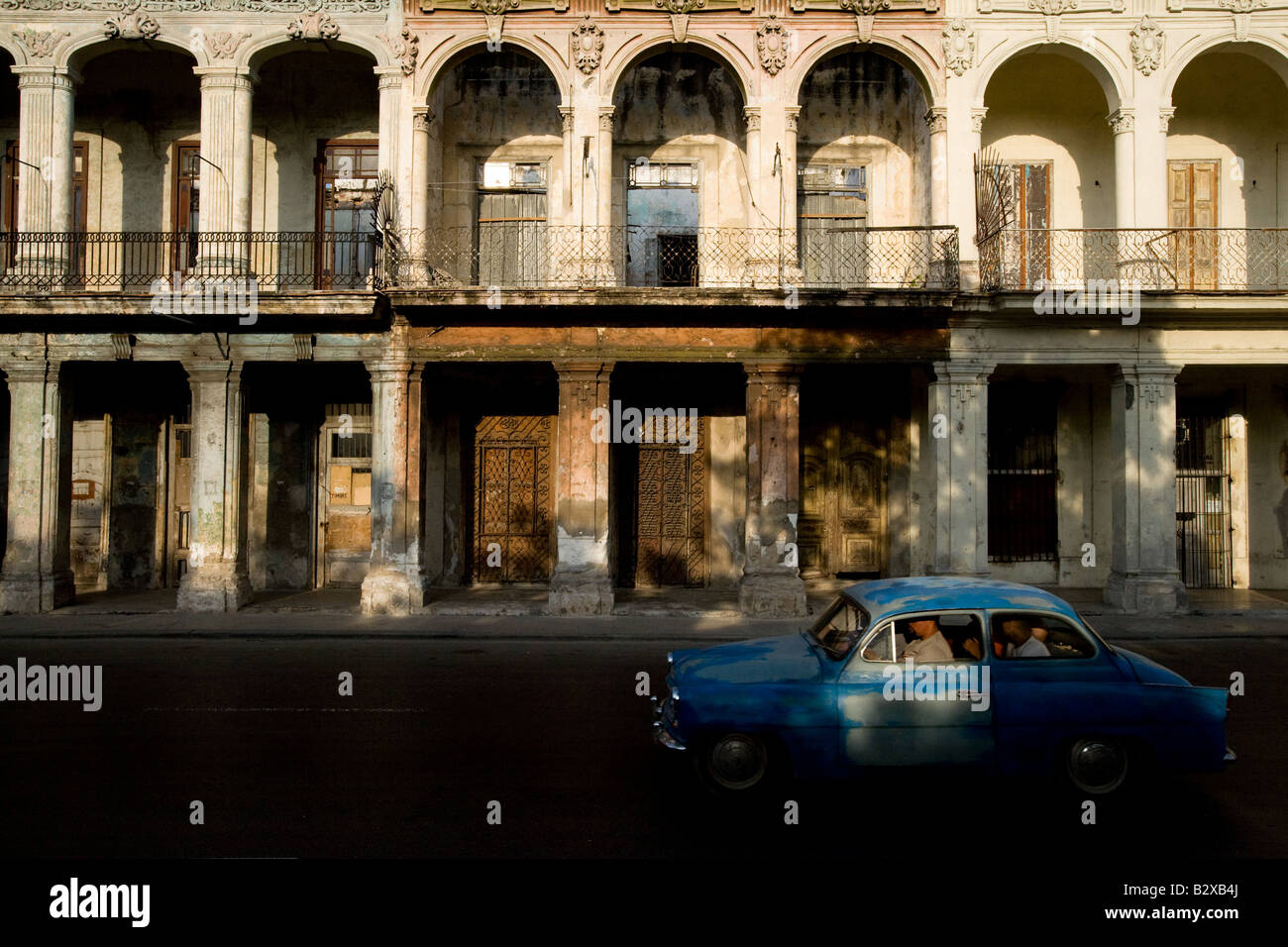 A vintage American can drives by run down colonial buildings in Old Havana, Cuba Stock Photo