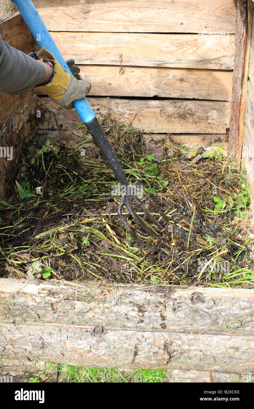 FILLING A COMPOST BIN MAKE SURE THE MATERIAL IS FORCED INTO THE CORNERS AND EVENLY SPREAD Stock Photo