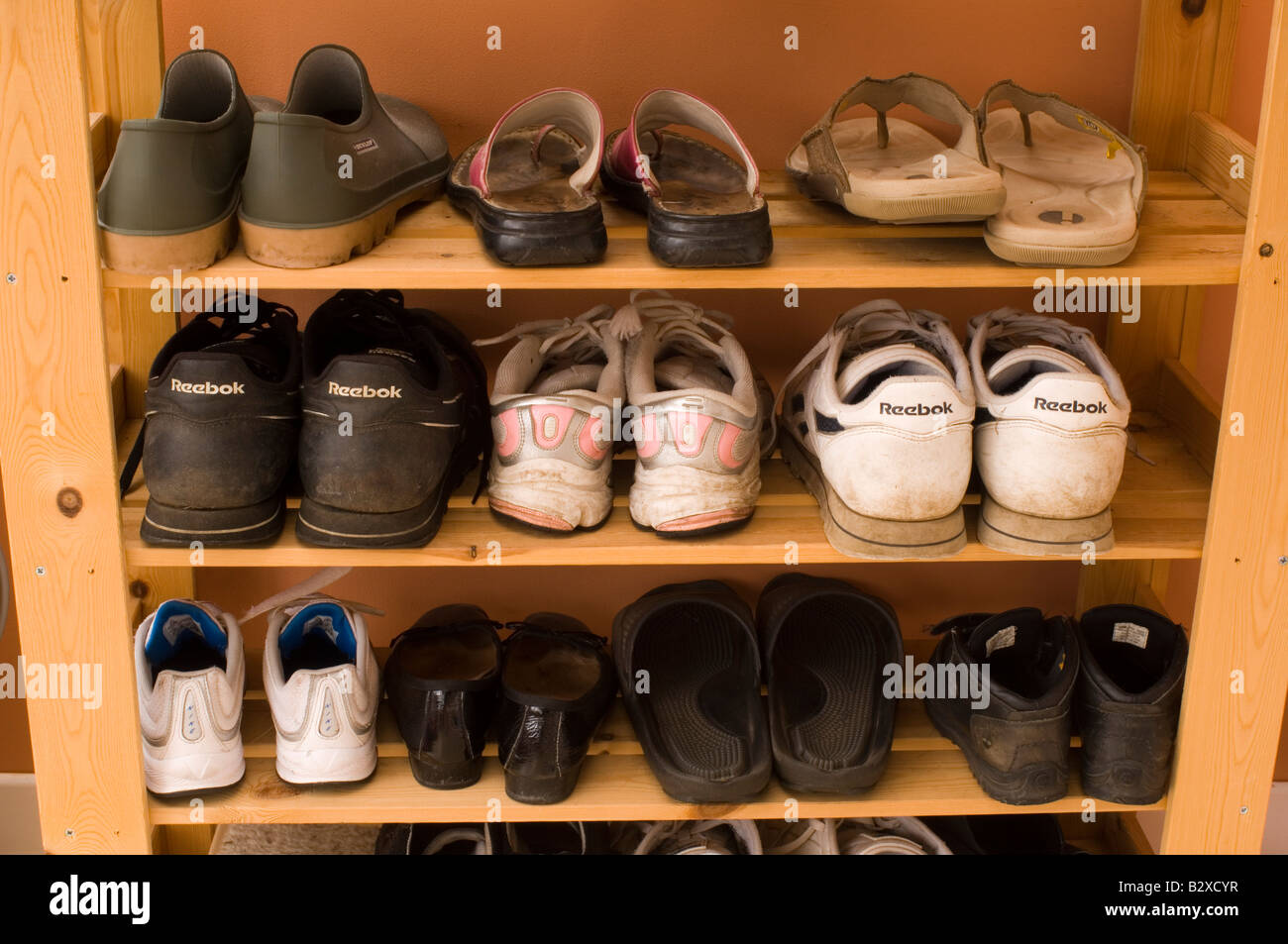 A Shoe rack housing lots of pairs of shoes and trainers Stock Photo