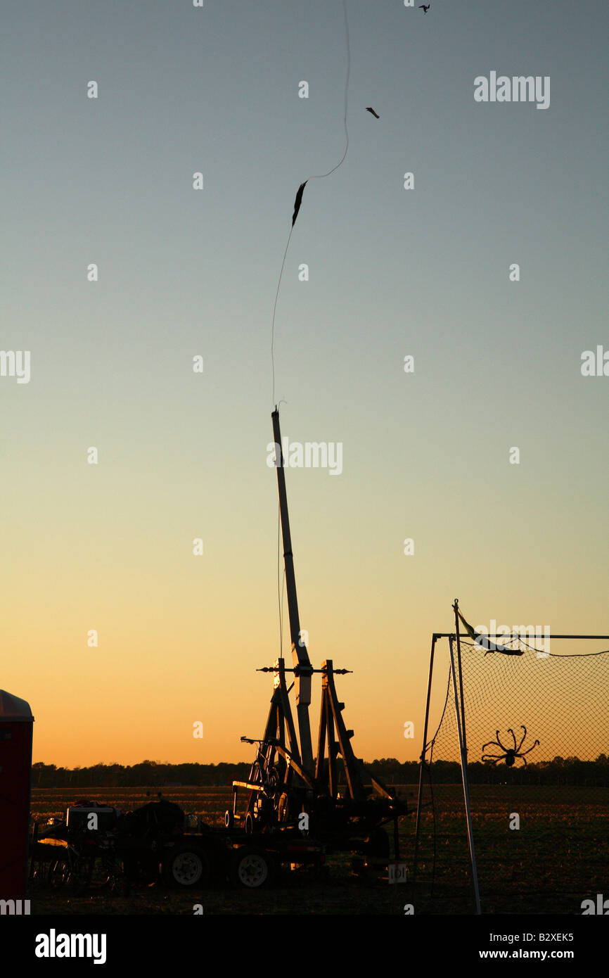 Wooden trebuchet with net behind at sunset.  Just completed a fling.  Arm is upright and sling is vertical line upwards. Stock Photo
