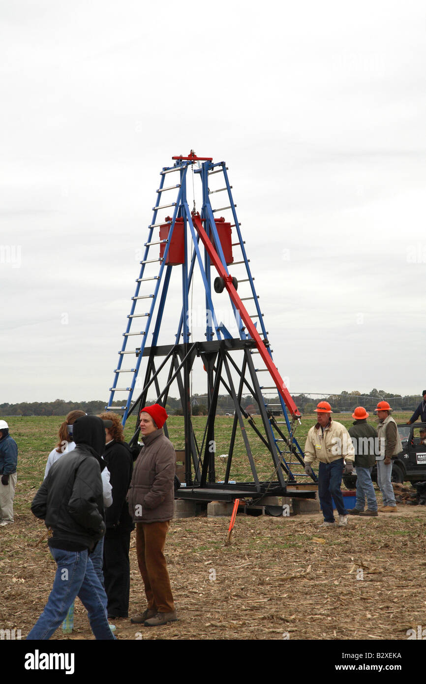 Large red and blue ‘ladder’ trebuchet with orange helmeted crew on right and few people talking on right. Stock Photo