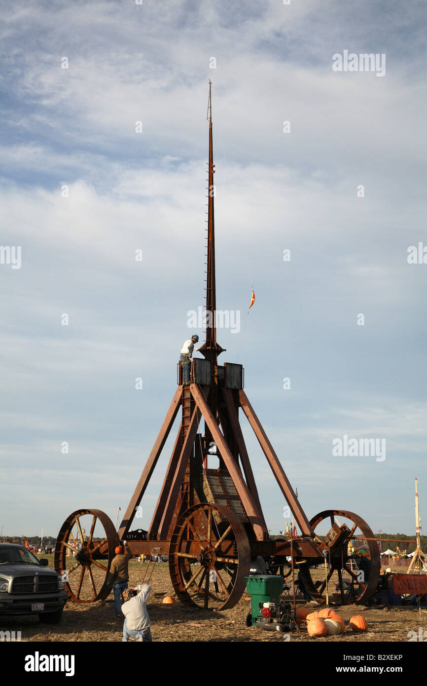 Huge iron wheeled Yankee Siege Trebuchet with person standing on small platform at base of tall arm high up on frame Stock Photo