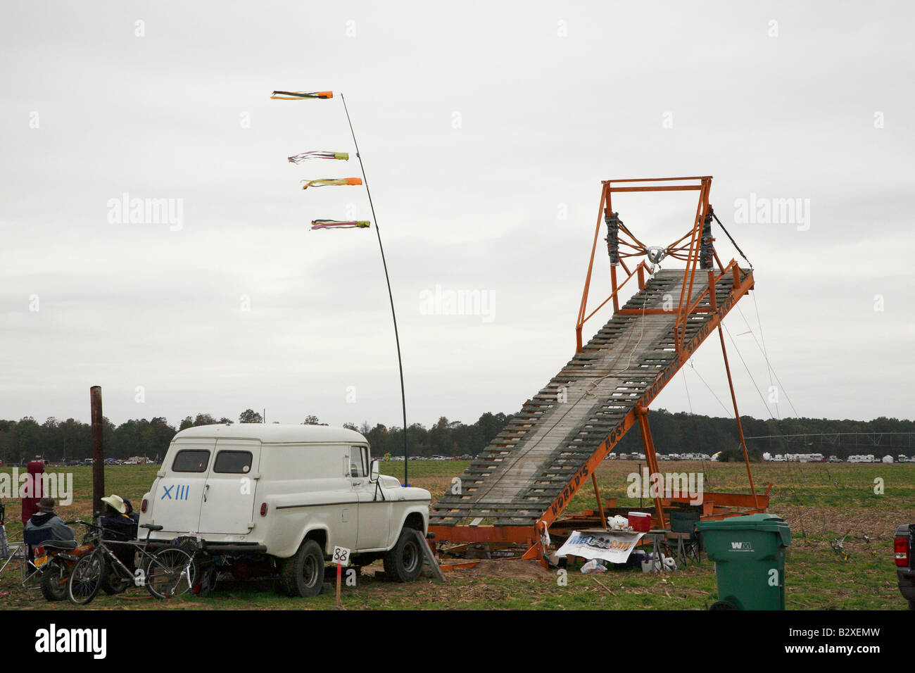 Long wooden ramp catapult with medieval flinging cup tied to rubber straps at top of ramp and rope to wind it back. Stock Photo