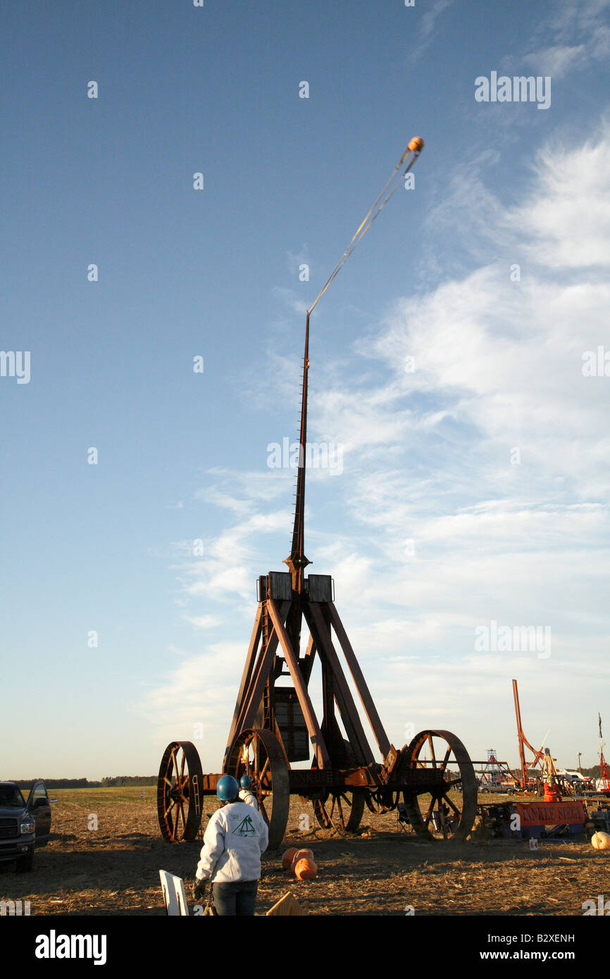 Huge iron wheeled Yankee Siege Trebuchet with fling arm straight up with pumpkin in sling at about 15 degree angle behind Stock Photo