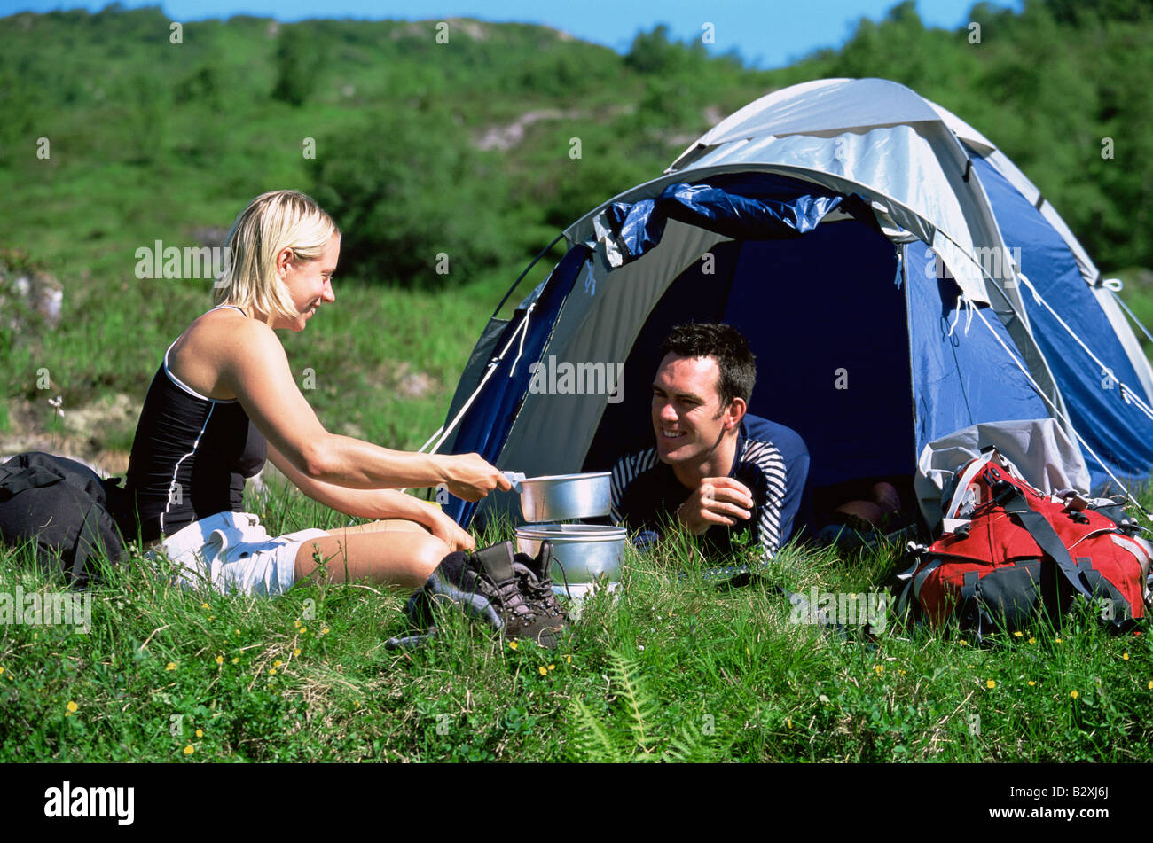 Couple outdoors at campsite with pots smiling (selective focus) Stock Photo