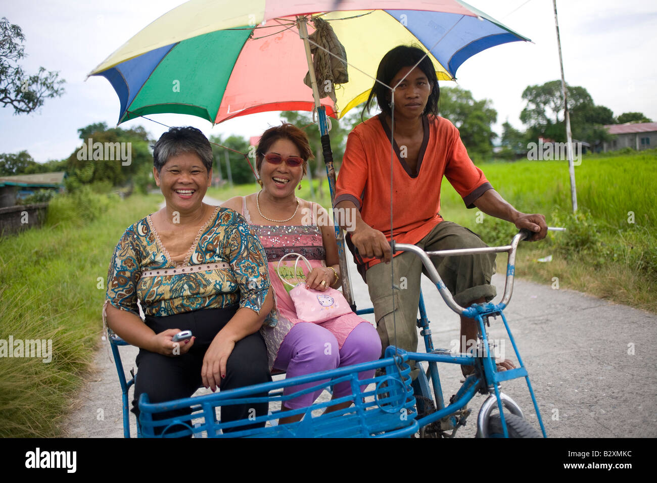 Two Filipinas ride a pedi tricycle taxi in Roxas, Oriental Mindoro, Philippines. Stock Photo