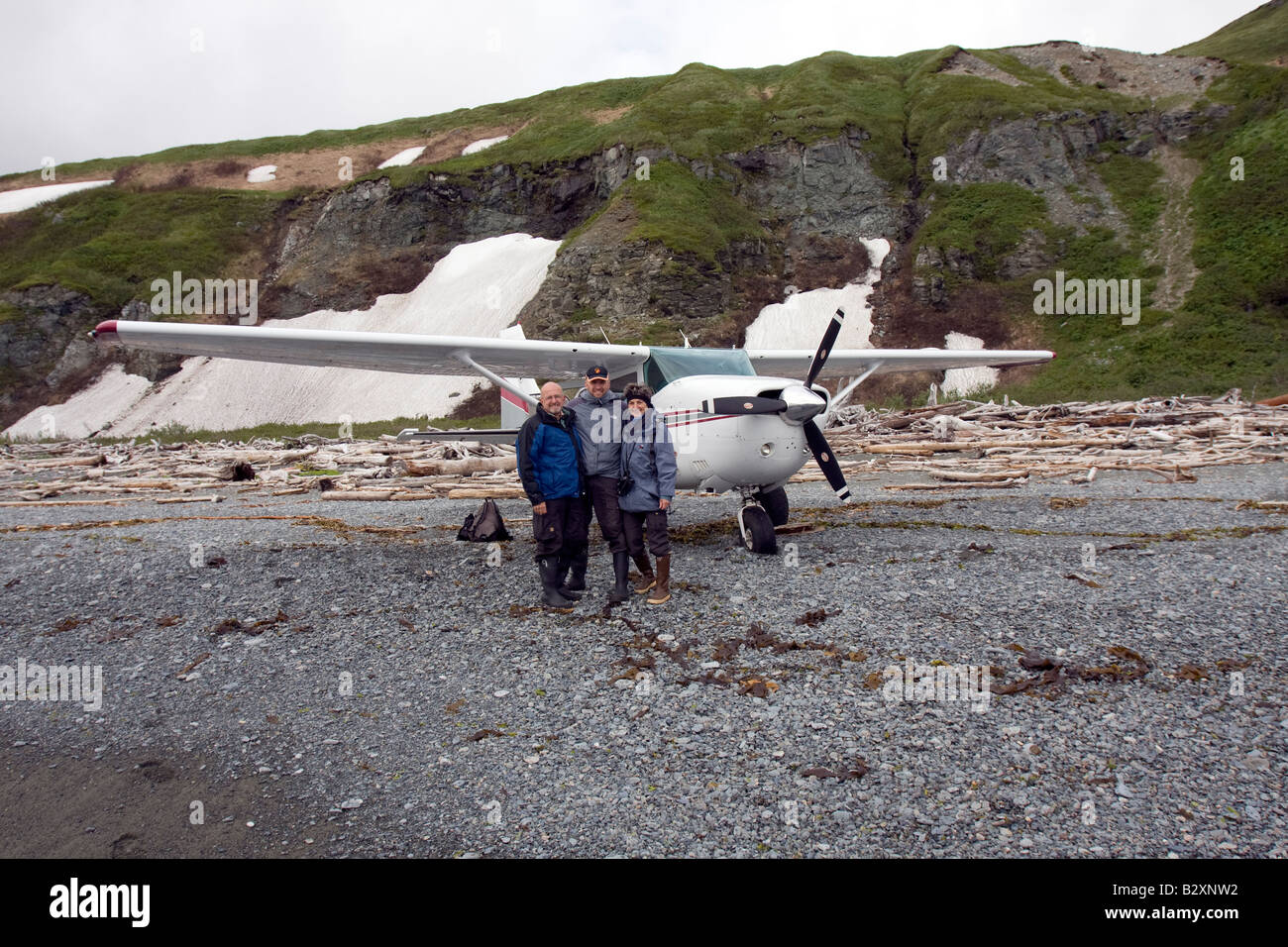 Tourists in front of small airplane that brought them to a driftwood covered beach in Katmai National Park and Preserve. Stock Photo