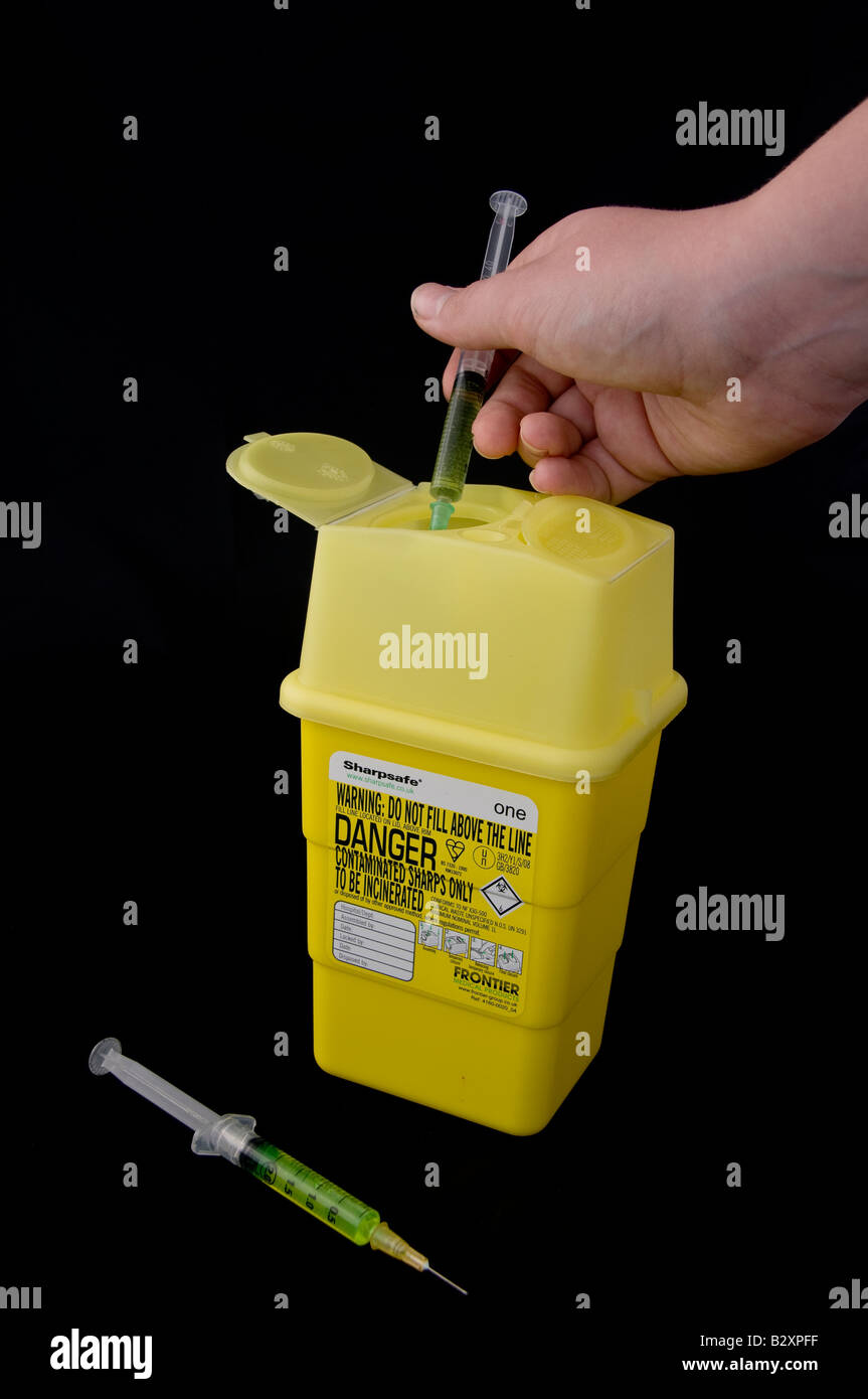 Disposing of syringes in a sharps box Stock Photo