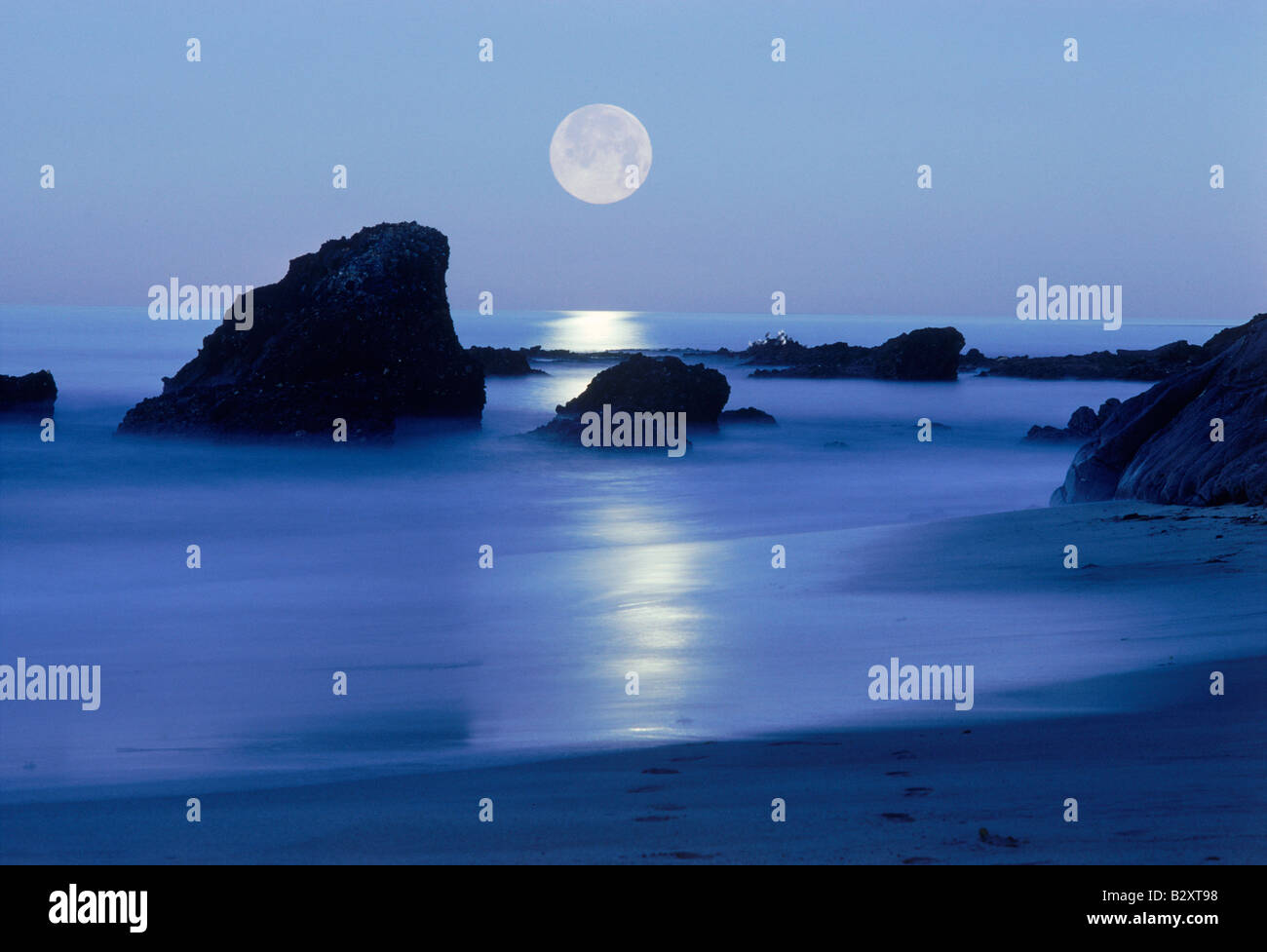 Moon setting over rocky shore along Pacific Coast in Laguna Beach ...