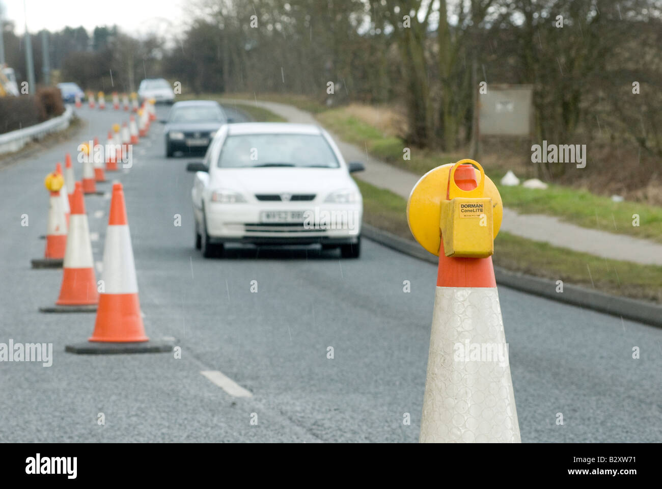 Traffic passing a yellow flashing light on top of a cone in roadworks