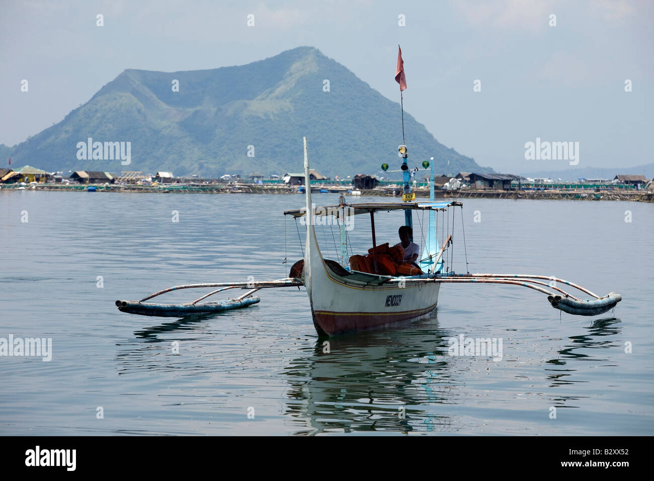 A Filipino maneuvers his boat on Taal Lake with a view of Volcano Island in the background near Tagaytay City, Philippines. Stock Photo
