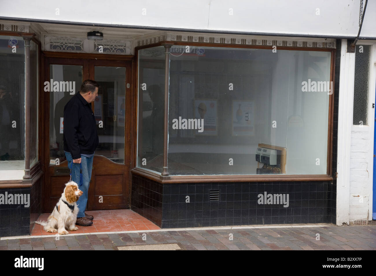 Man and dog looking in window of empty shop Stock Photo