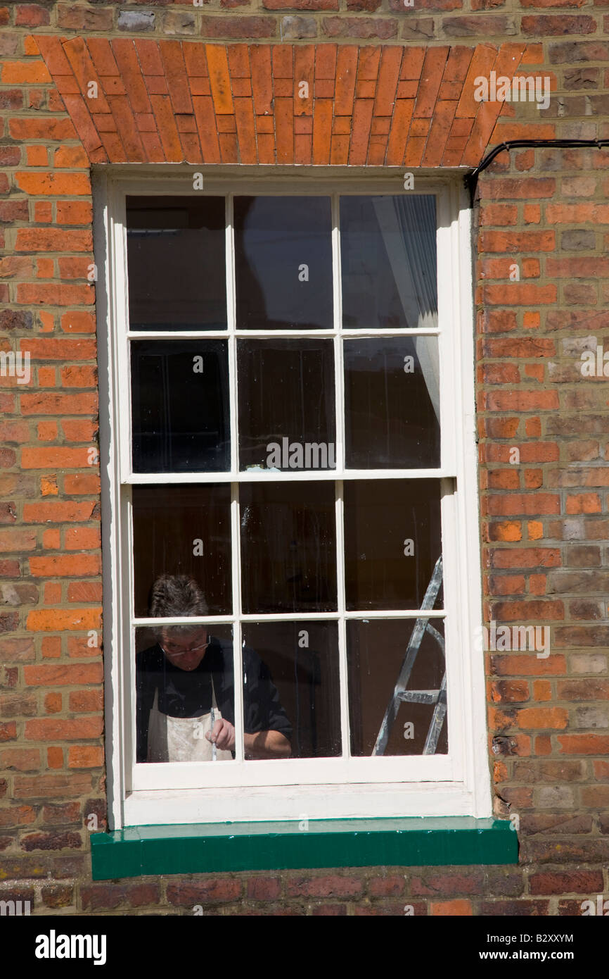 Painter painting the inside of an old sash window Stock Photo