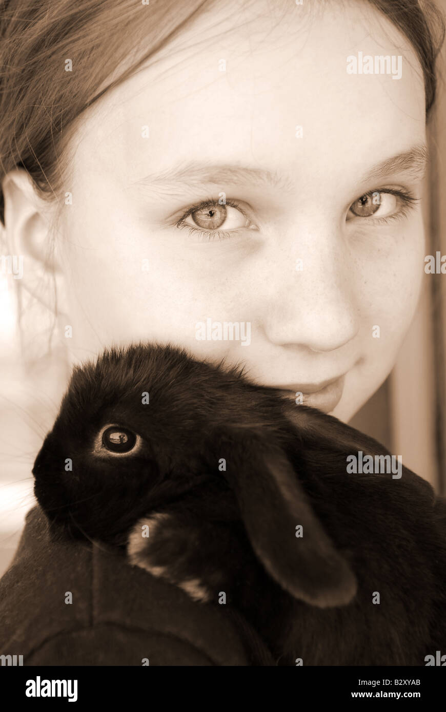 Portrait of a young girl holding a black baby rabbit in sepia Stock Photo