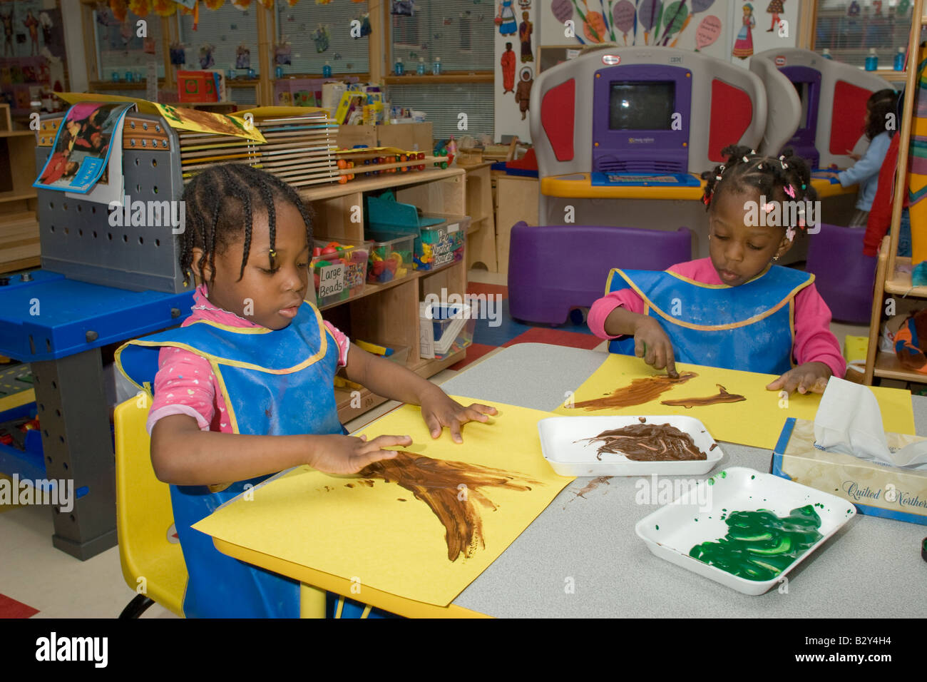 Two 4 year old African American girls finger painting in preschool class Stock Photo