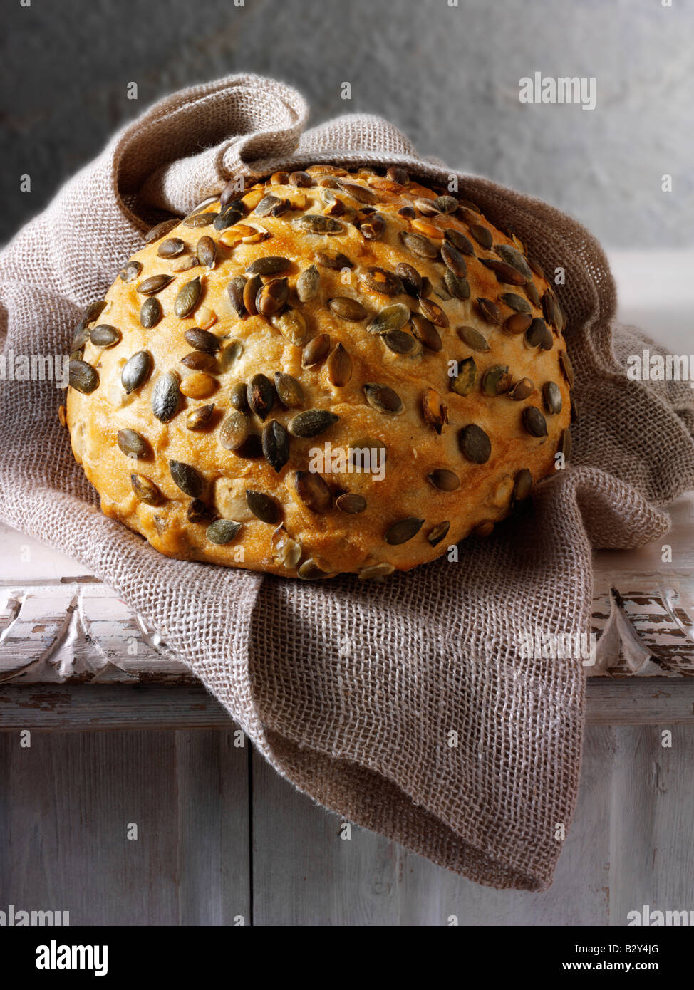 Artisan Pumpkin seed loaf of bread  in a rustic setting on a table Stock Photo