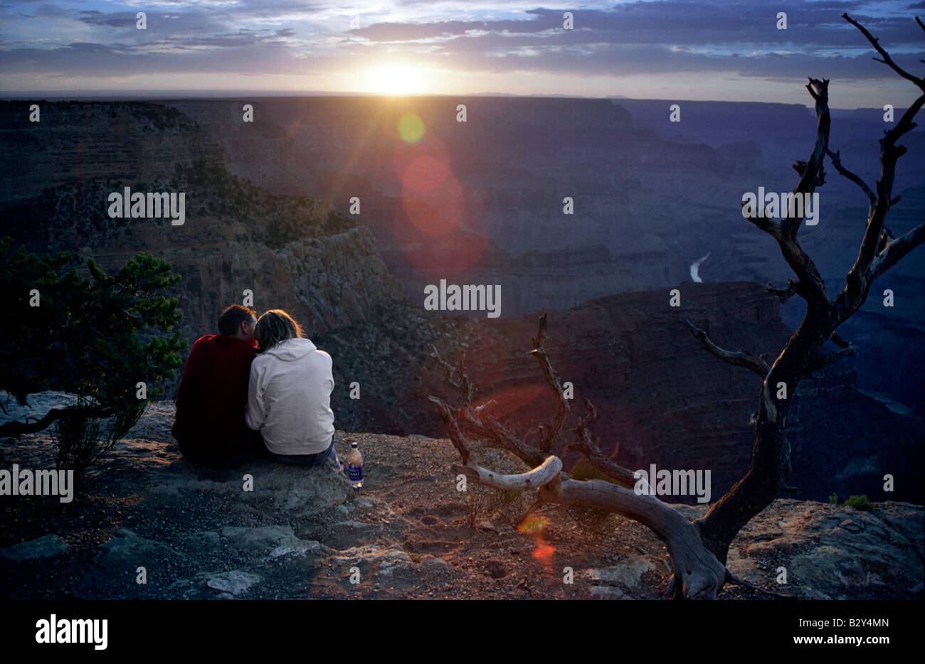 A man and a woman sit together at the edge of the Grand Canyon at ...