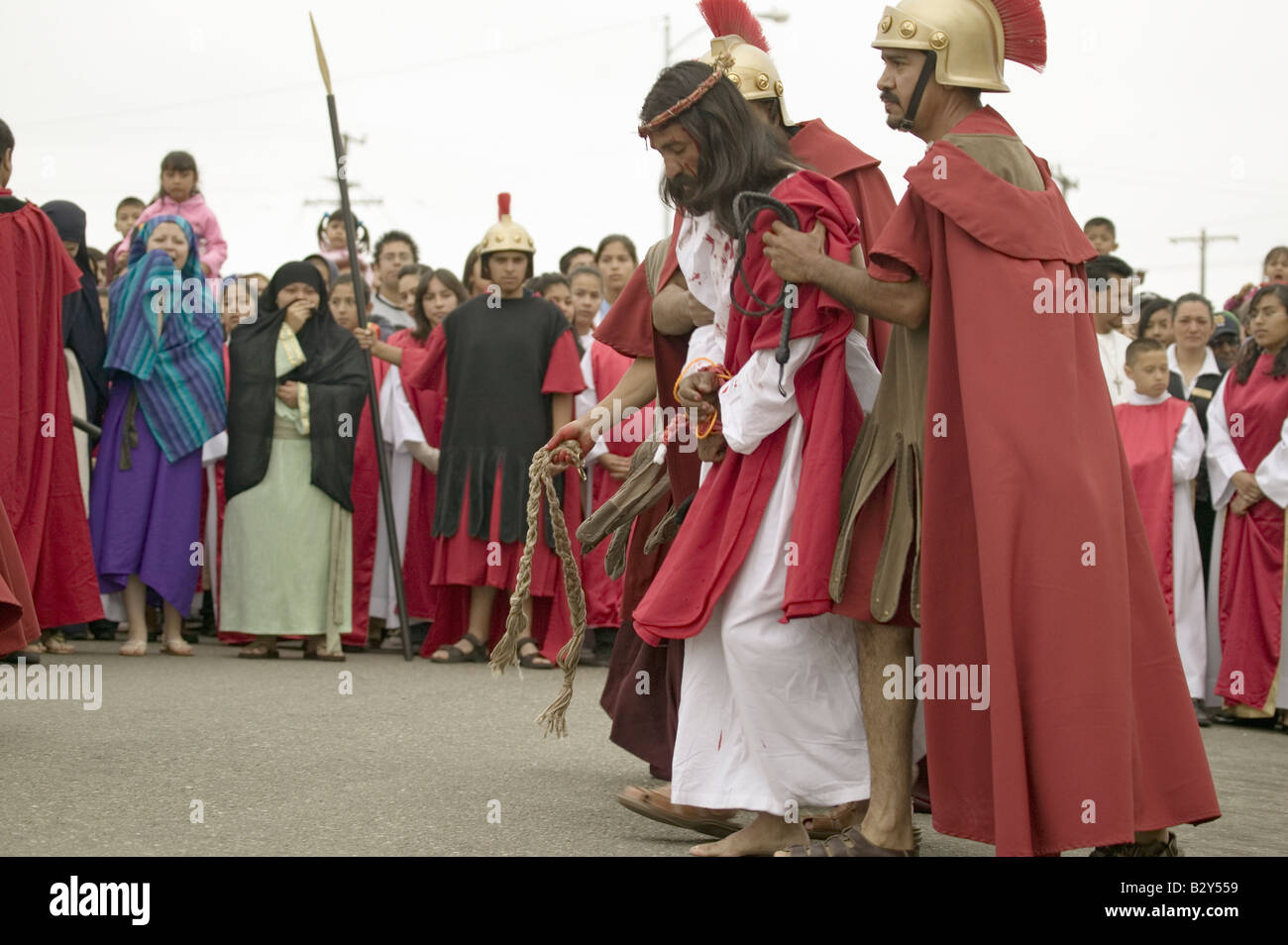 An actor portraying Jesus Christ carrying a cross past crowds on Good ...