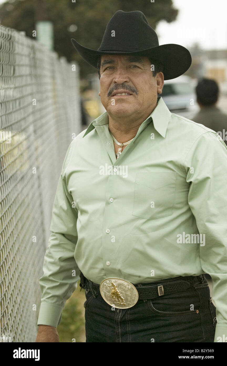 A Hispanic man in a green shirt with a large western belt and cowboy hat, in Oxnard, California Stock Photo