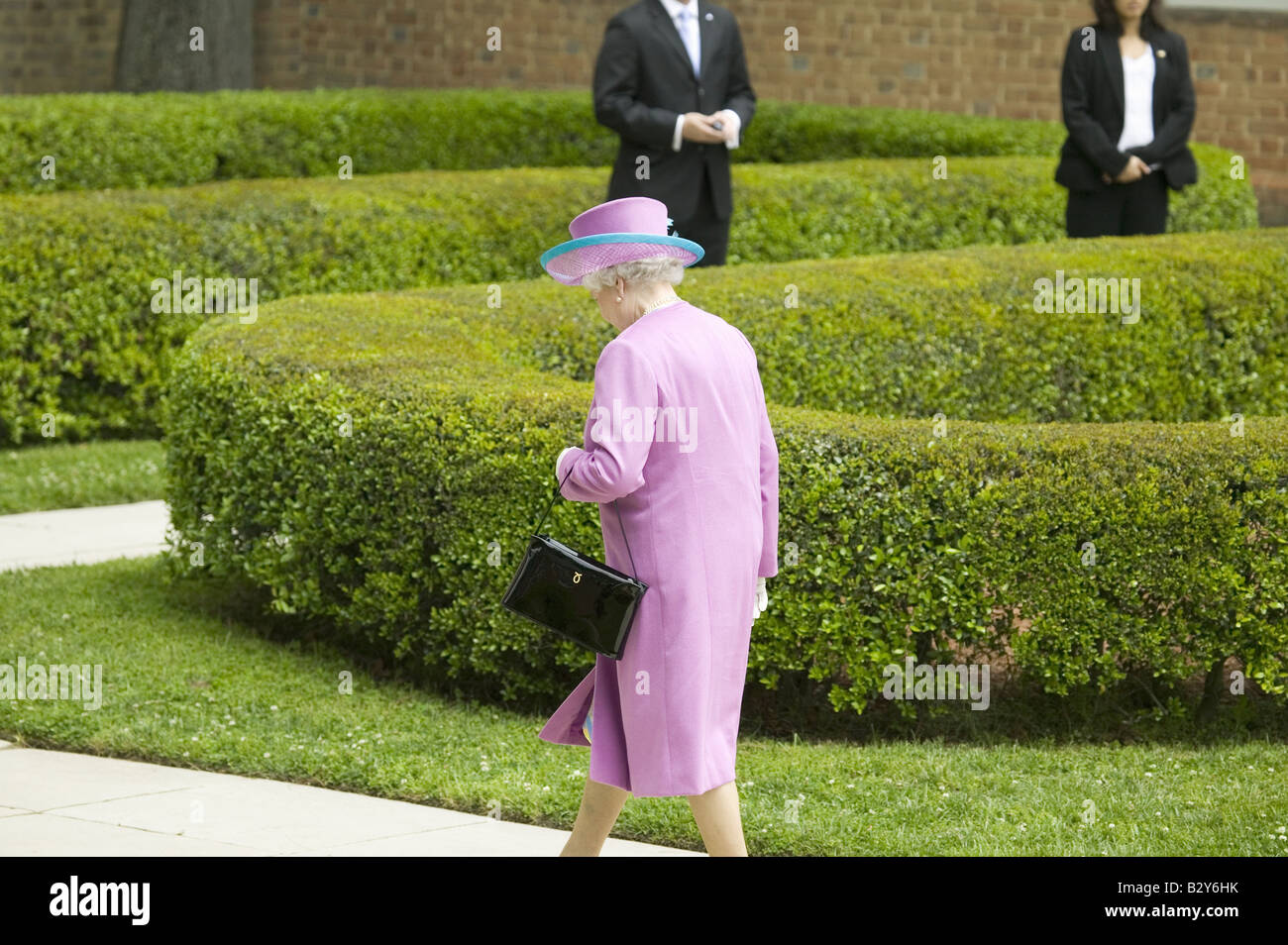 Queen Elizabeth II in bright purple outfit and black purse, walking to Governor's Palace in Williamsburg VA Stock Photo