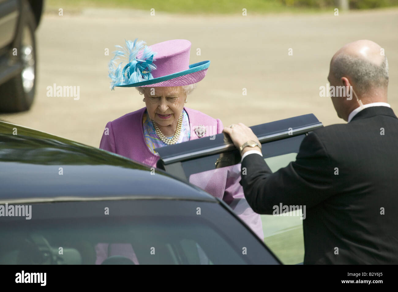 Queen Elizabeth II in bright purple outfit and hat, entering Presidential Limousine in Williamsburg VA Stock Photo