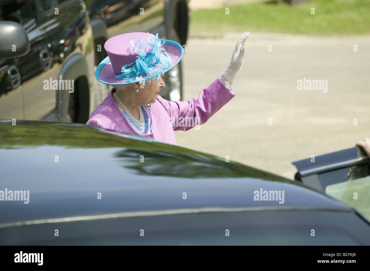 Queen Elizabeth II in bright purple outfit and hat, waving as she enters Presidential Limousine in Williamsburg VA Stock Photo