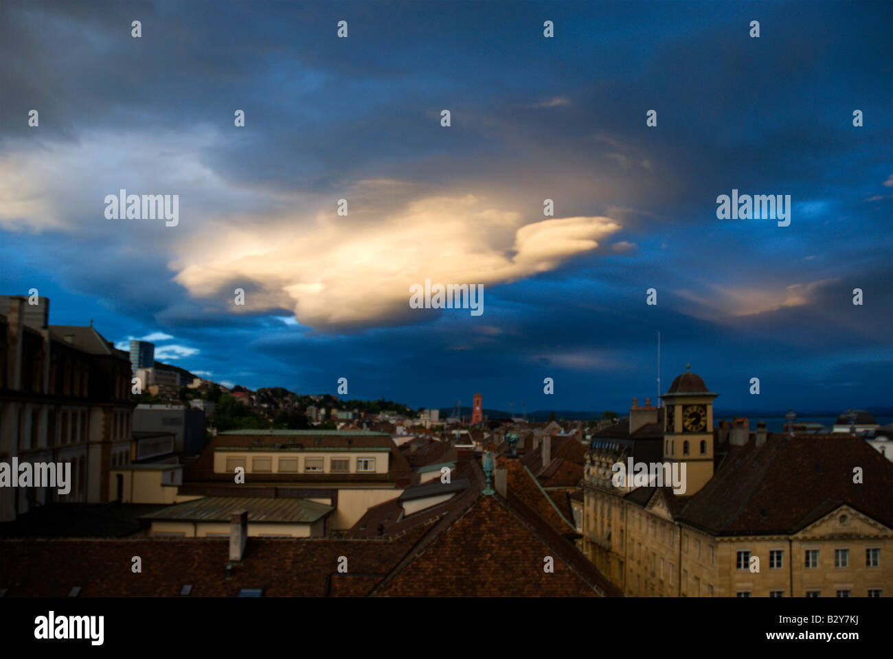 Beautiful blue sky with gray storm clouds passing over the city of Neuchatel, Switzerland.  Evening is approching. Stock Photo
