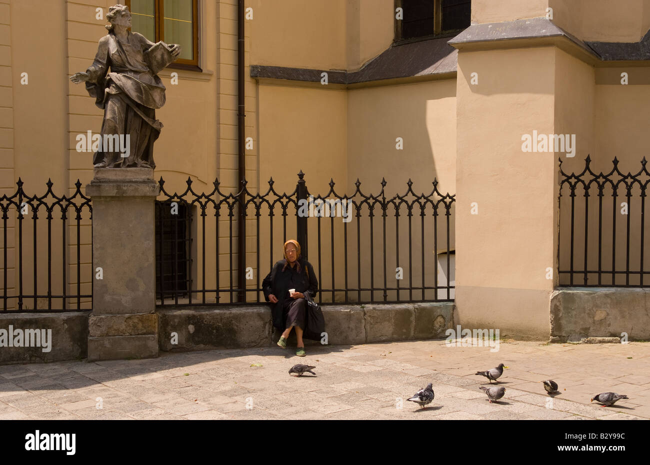 Old lady babushka sitting in downtown city center feeding pigeons in ...