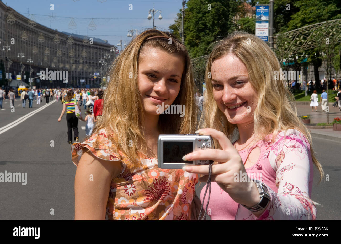 Two teenage girls taking self portrait with camera in street festival of closing the main street Khrechatk Street Kiev Ukraine Stock Photo