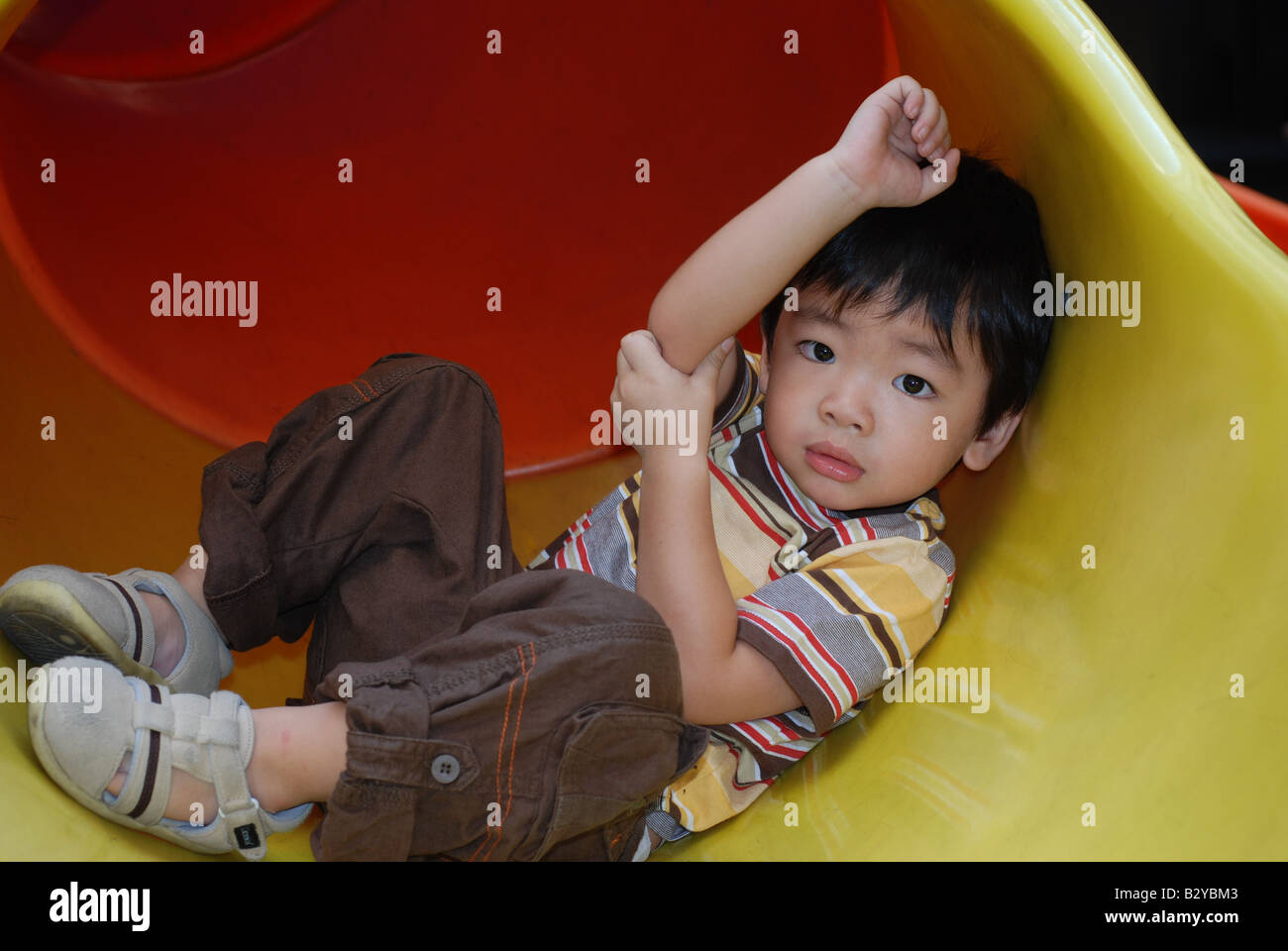 Chinese boy sitting on slide in playground Stock Photo - Alamy