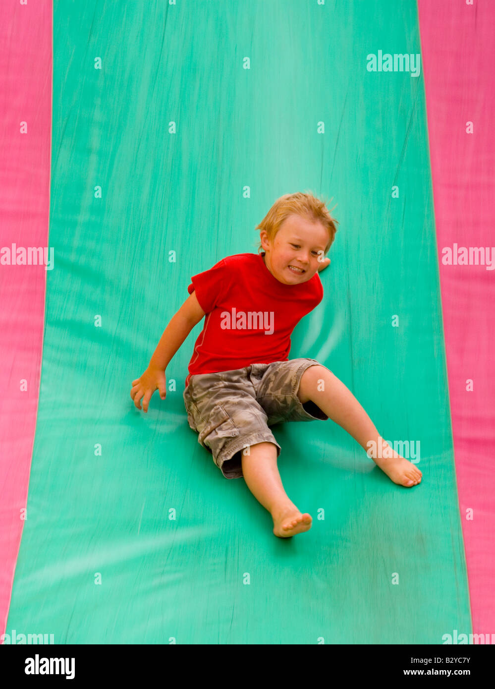 Four year old boy on bouncy castle slide Stock Photo Alamy