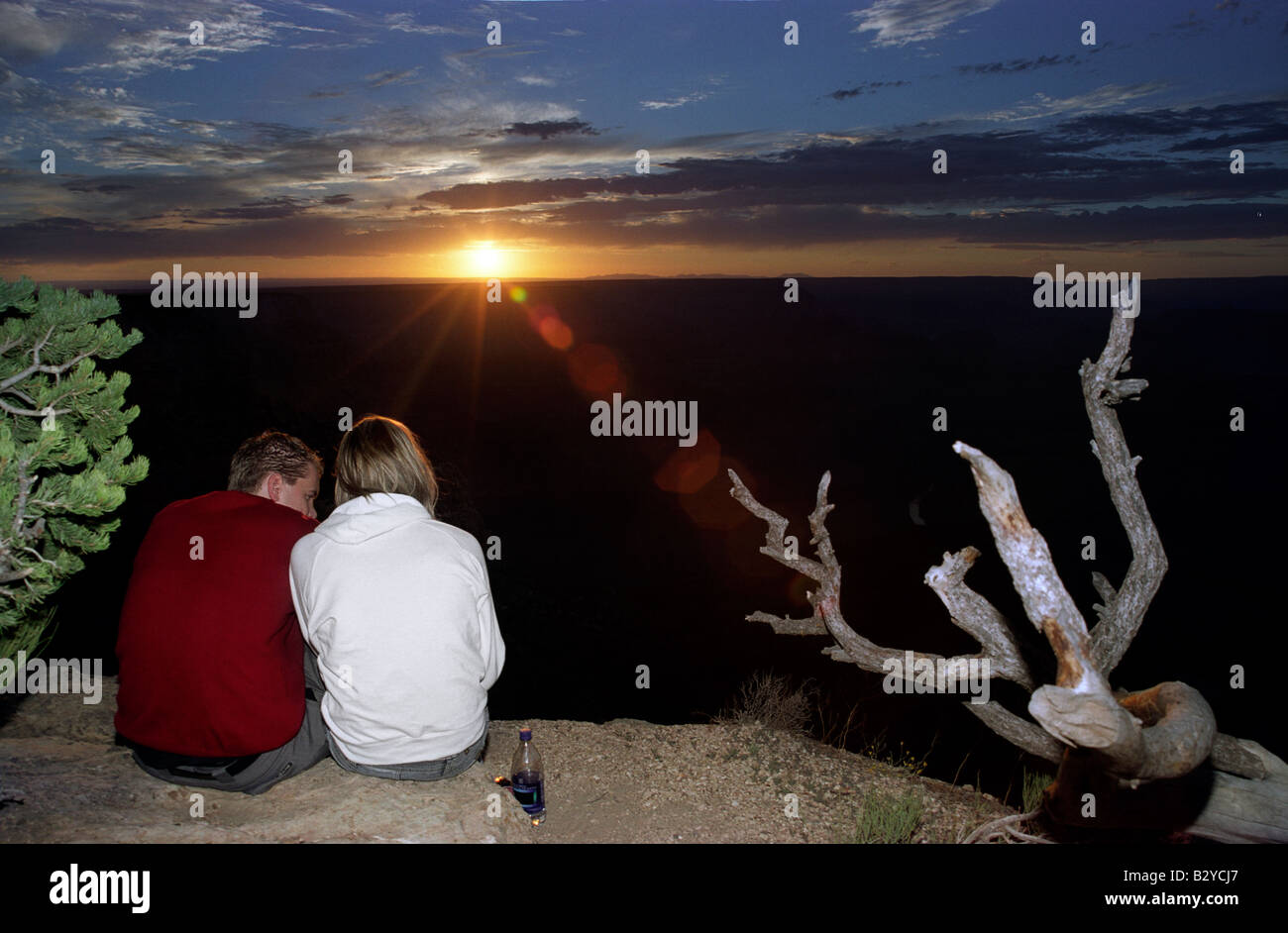 A man and a woman sit together at the edge of the Grand Canyon at ...