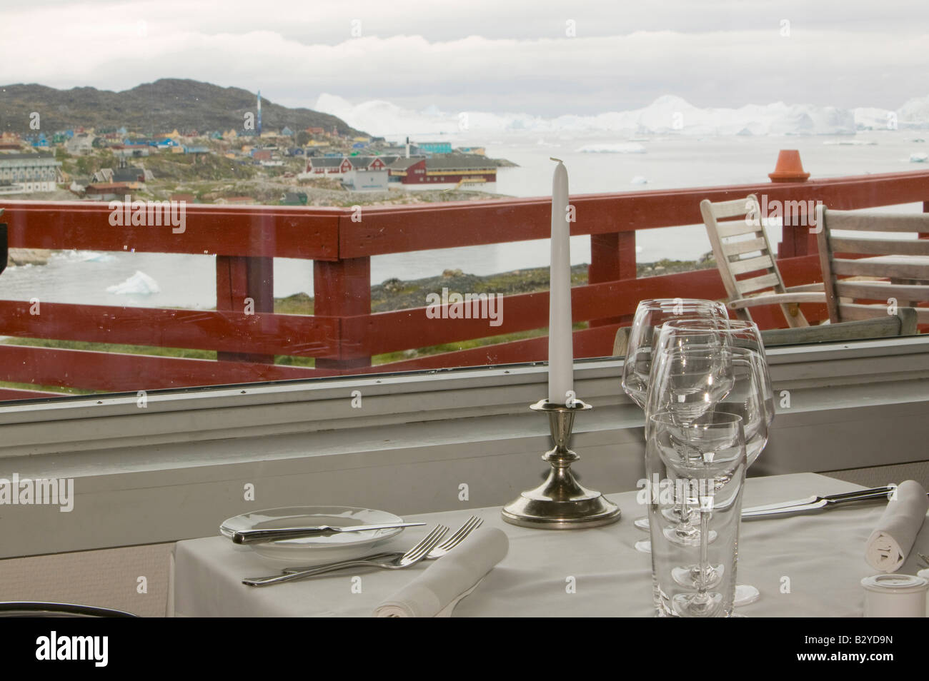 A place setting in the restaurant of the Arctic Hotel in Ilulissat on Greenland with icebergs in the background Stock Photo