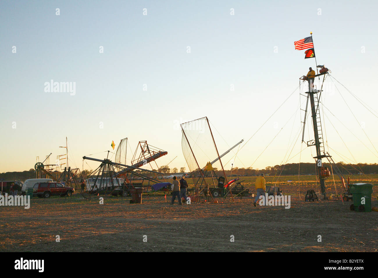 Group of pumpkin flinging machines with large catapult on right with man at top (Fibonacci - world record holder) and others Stock Photo