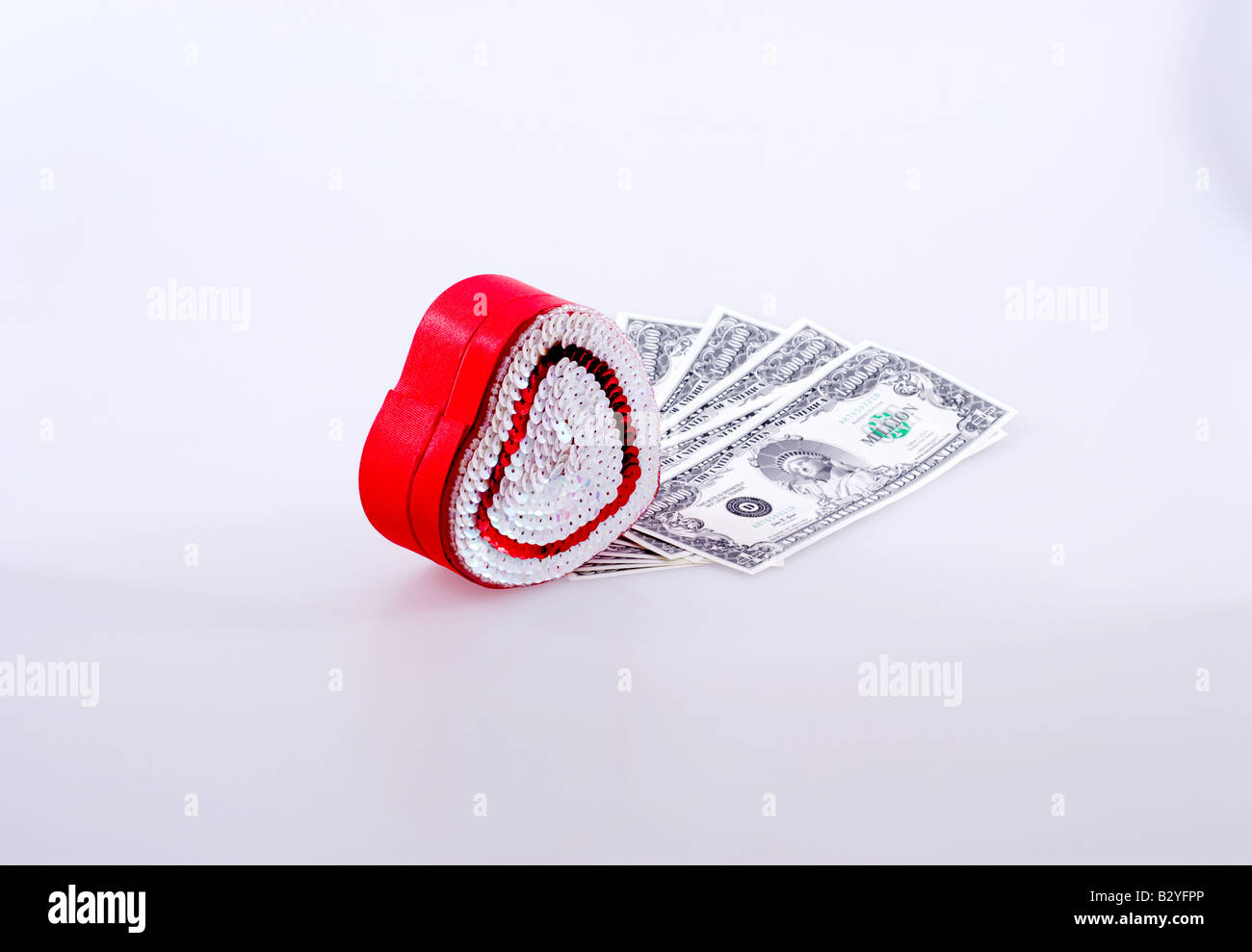 Small heart-shaped candy box next to fake million dollar bills Stock Photo
