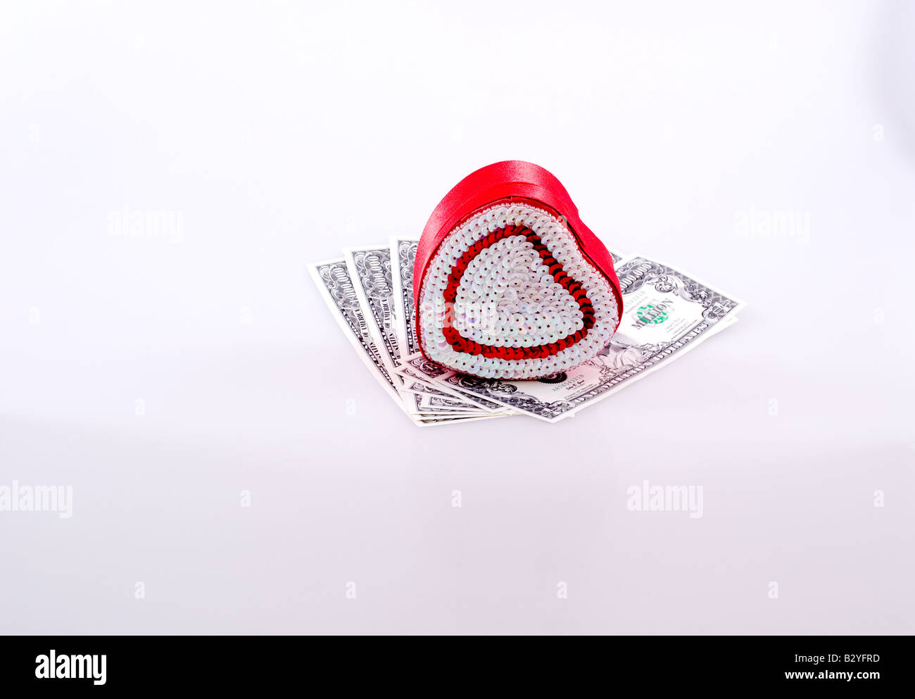 Small heart-shaped candy box atop fake million dollar bills Stock Photo