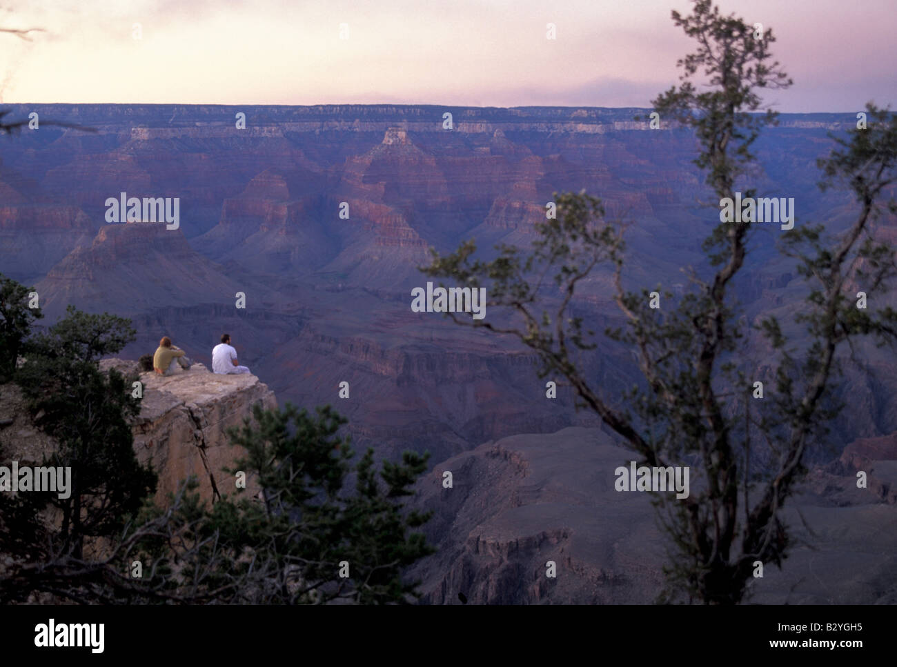 A man and a woman sit together at the edge of the Grand Canyon at ...