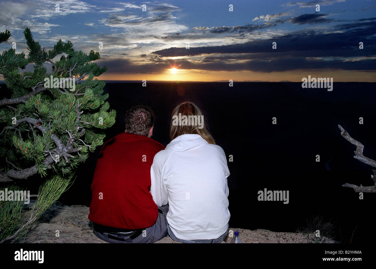 A man and a woman sit together at the edge of the Grand Canyon at ...