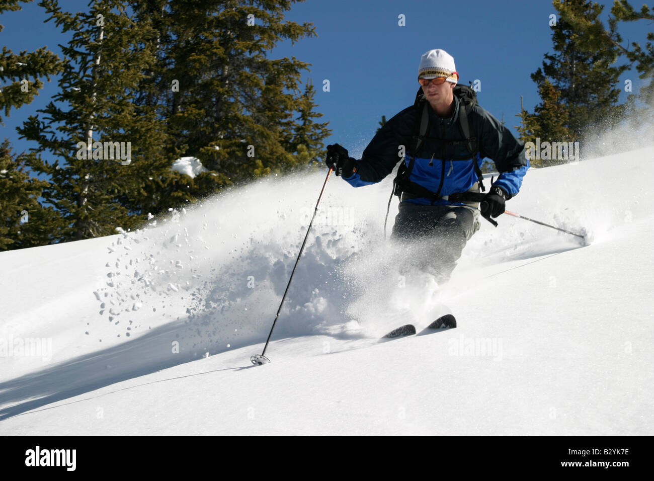 A man skis in fresh powder with blue skies. Stock Photo