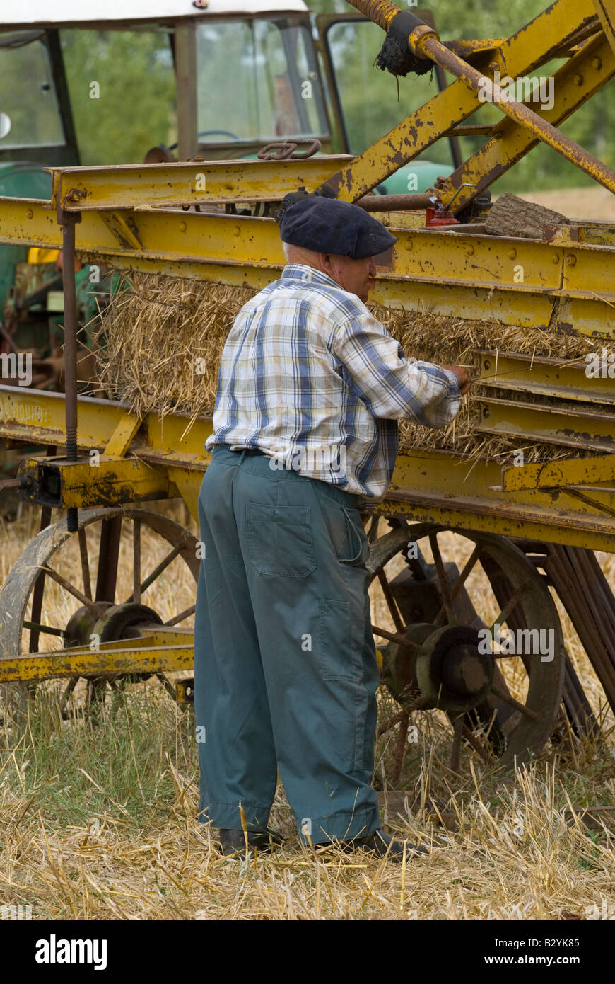 French peasant working on old straw baler machine at agricultural show, Indre, France. Stock Photo