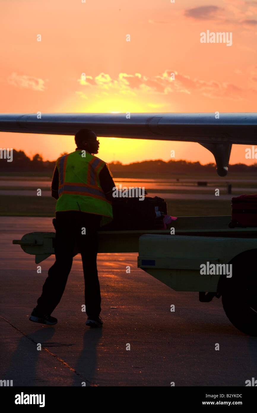 A commercial airplane sits on the tarmac as luggage is loaded at the Springfield-Branson National Airport during sunset Stock Photo
