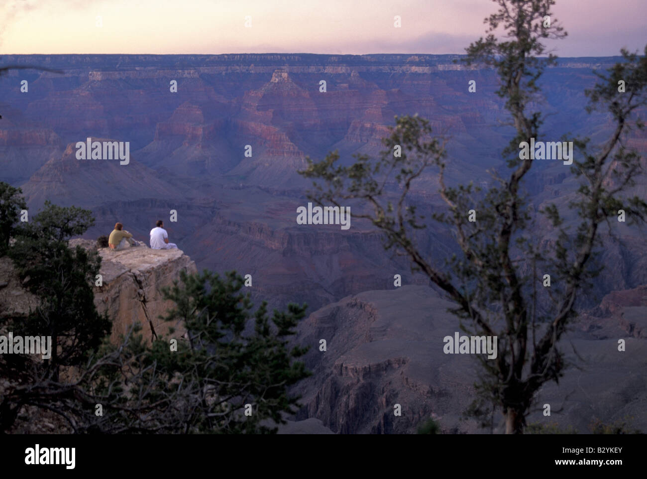 A man and a woman sit together at the edge of the Grand Canyon at ...