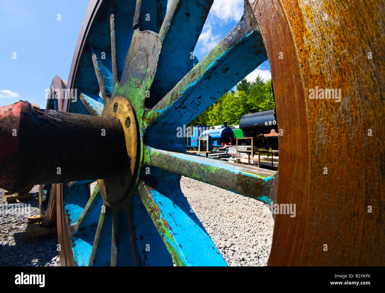 Steam Train scrapyard looking through a large metal rusty train wheel Stock Photo