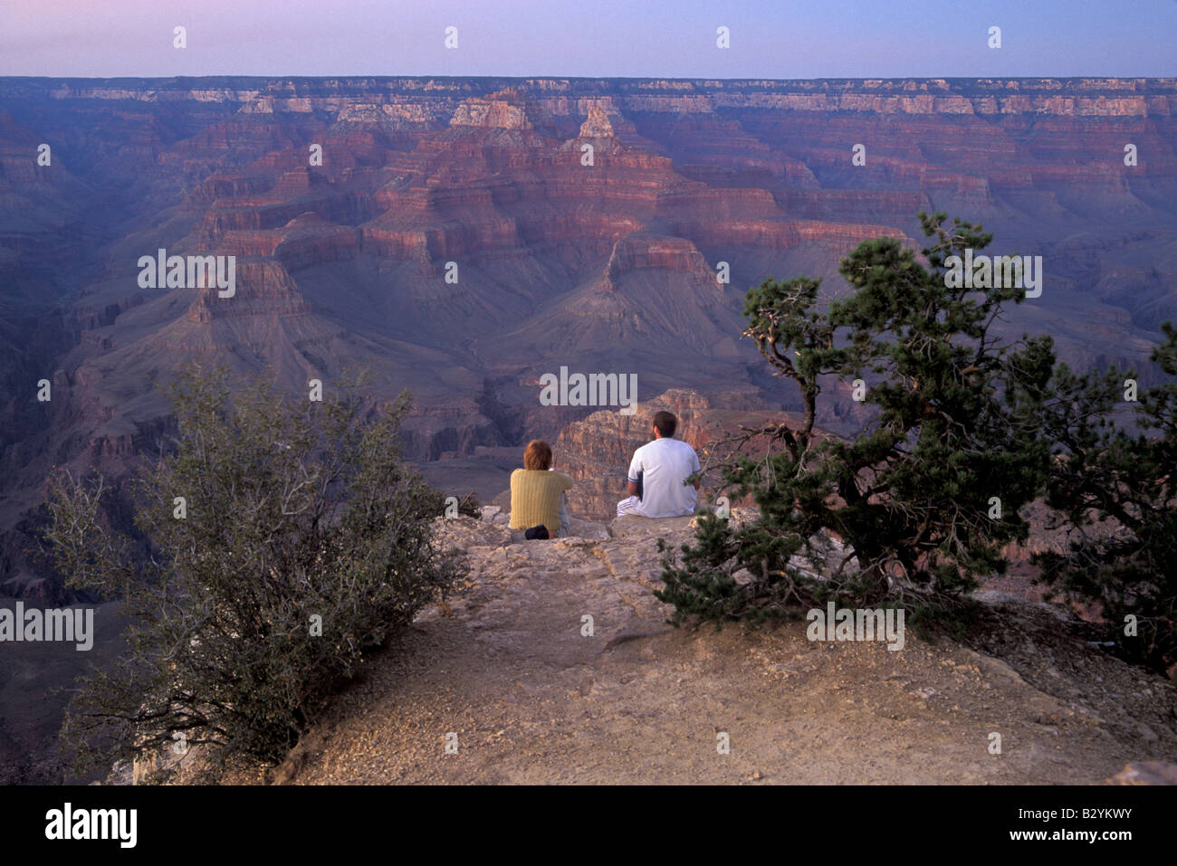 A man and a woman sit together at the edge of the Grand Canyon at ...