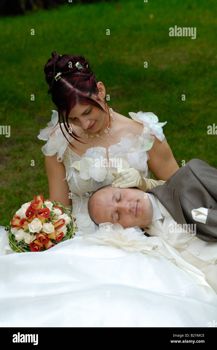 Newlywed couple with husband asleep on his wife in bench's park, France Stock Photo