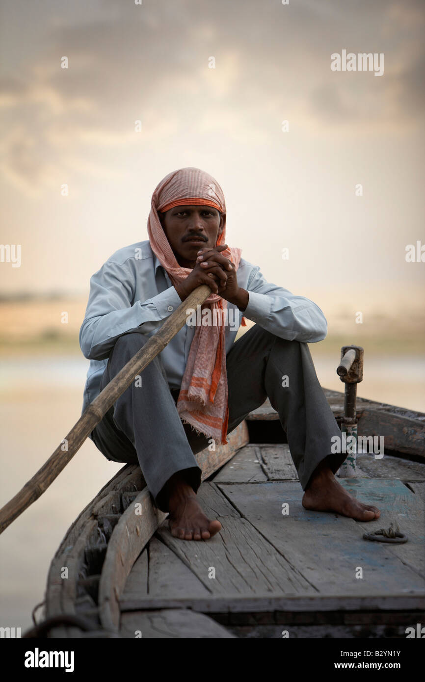 A portrait of an Indian man sitting on the bow of his wooden boat. Stock Photo